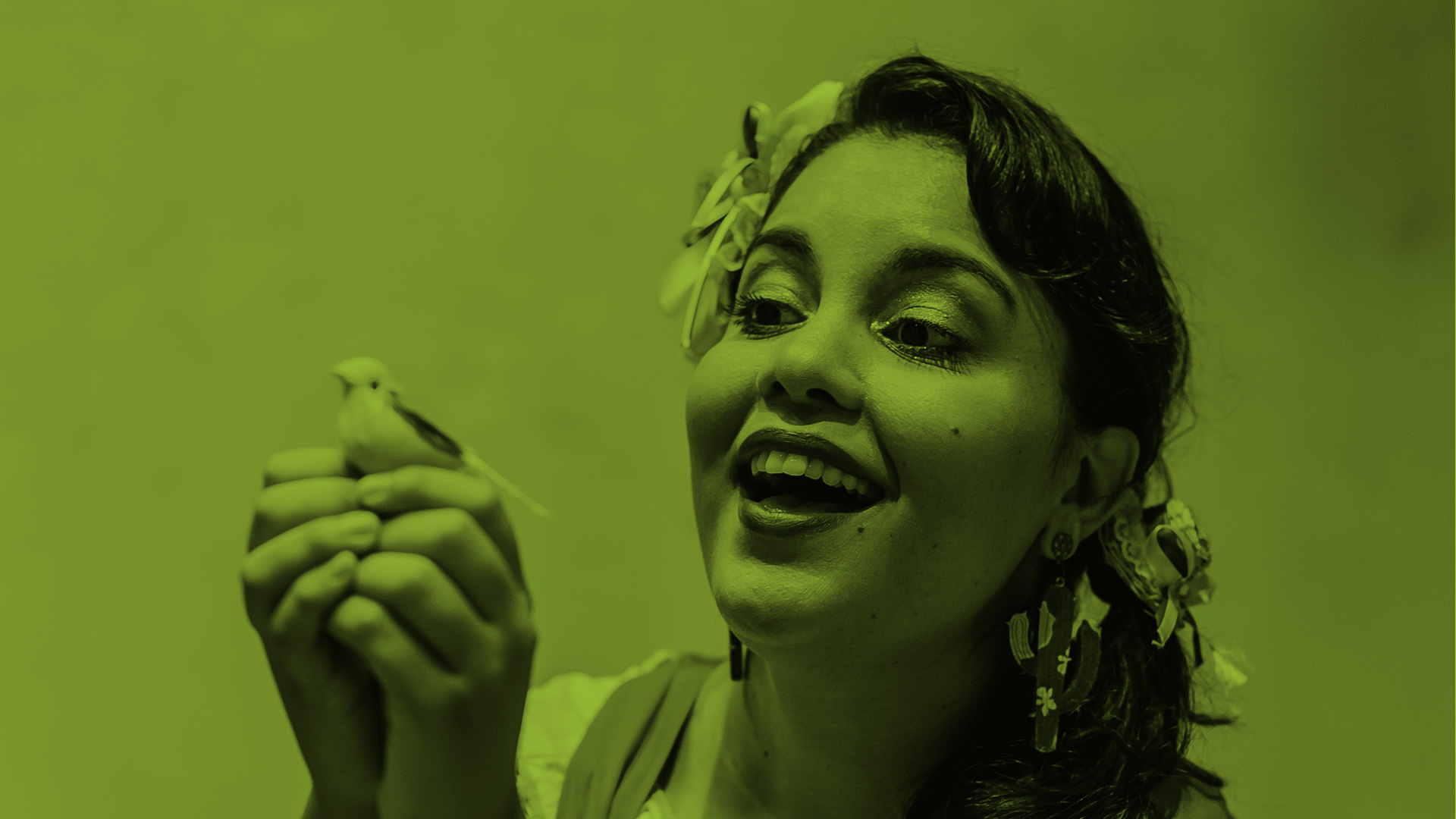 Fotografia com filtro verde, característico do podcast. Na imagem, Mari Bigio segura um passarinho.
