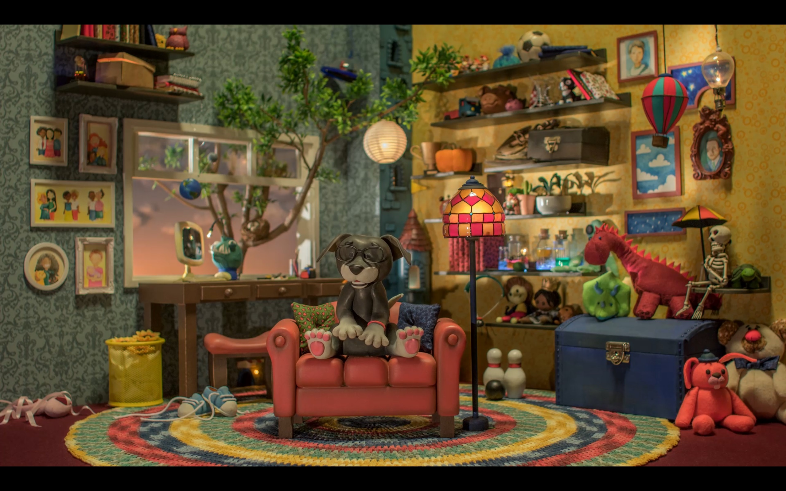 Em um fundo de um quarto com brinquedos, tem um cachorro sentado em um sofá